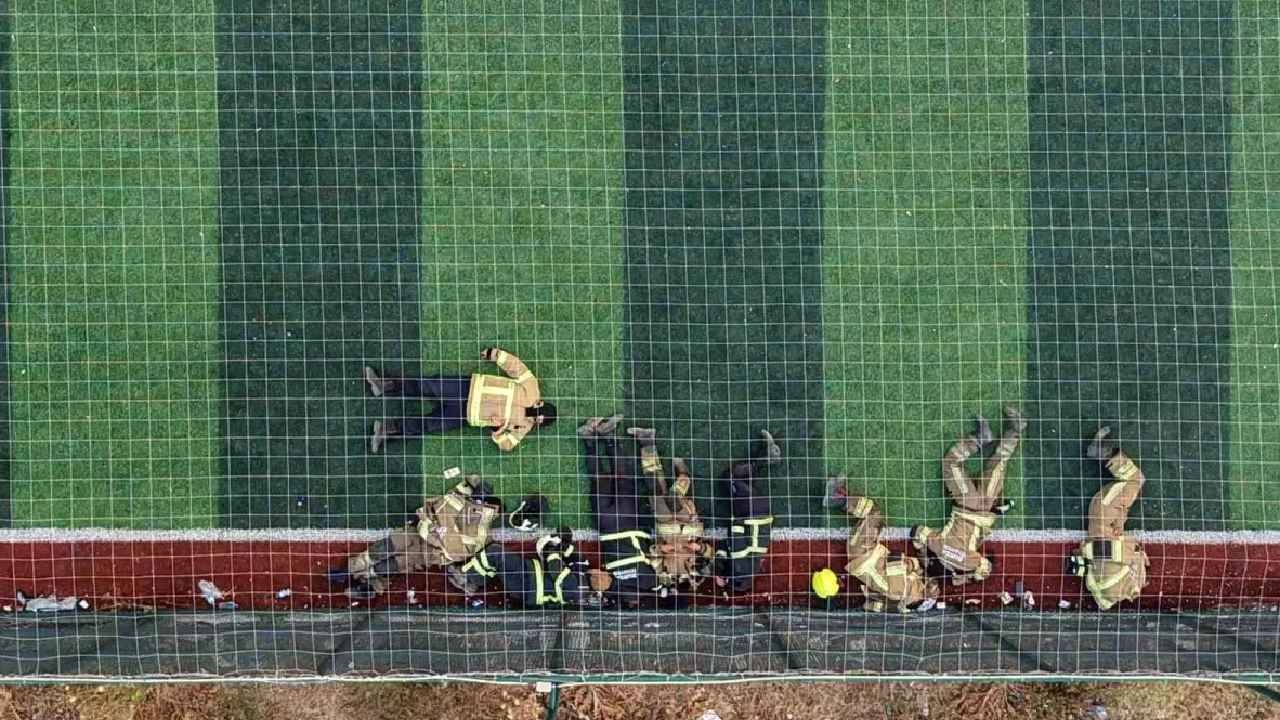 Los bomberos que luchaban contra las llamas descansaron en el campo de césped artificial.