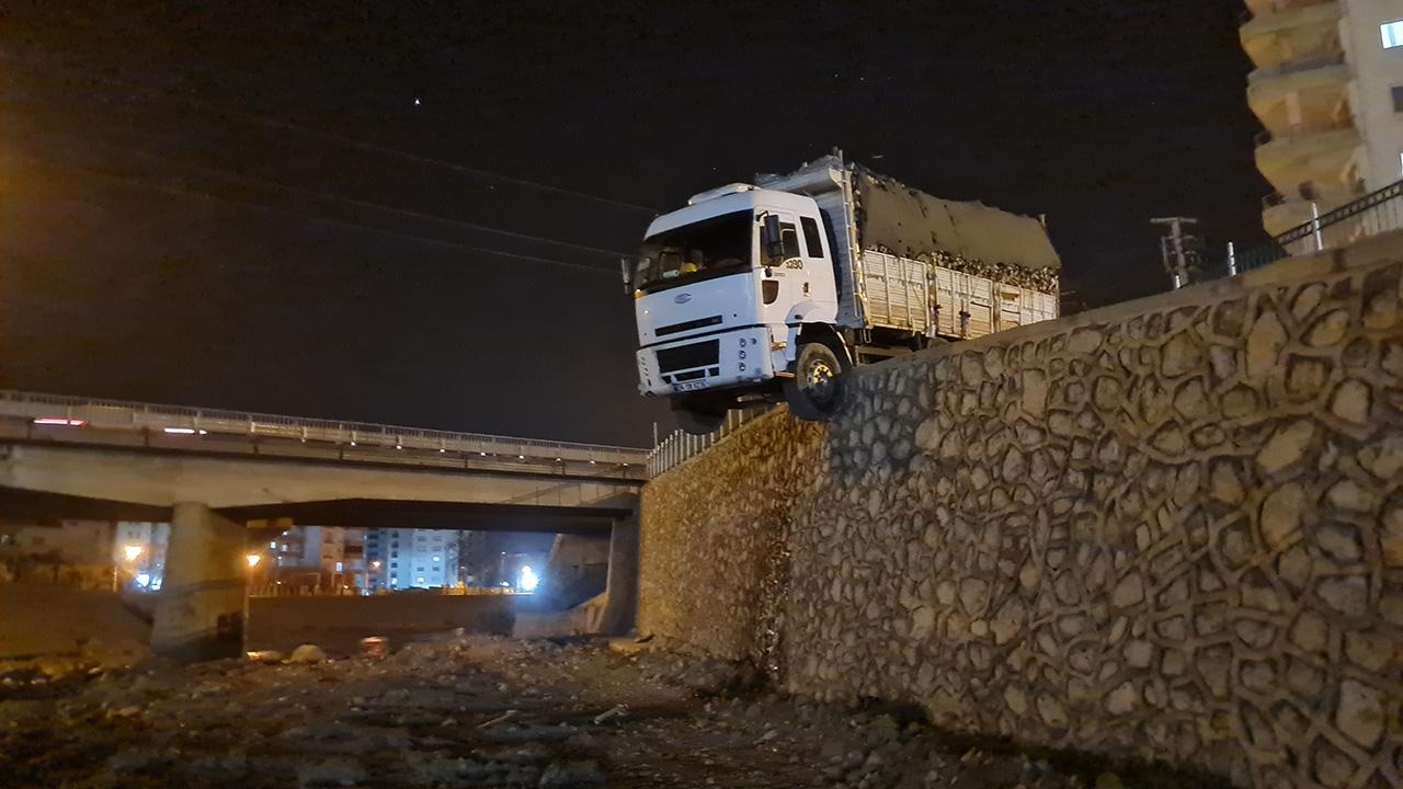 Truck loaded with wood stuck on retaining wall, driver not found